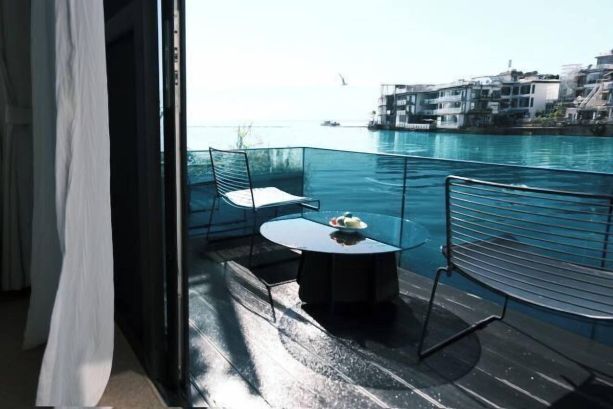 A balcony with a table and chairs, overlooking a body of water and buildings.
