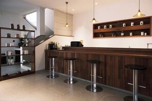 A modern kitchen with a bar area, bar stools, and a staircase. - Don't Think About The Elephant Hostel (Dali City)