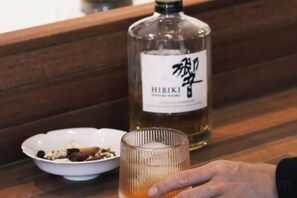 A bottle of Hibiki whiskey and a glass on a wooden surface. - Don't Think About The Elephant Hostel (Dali City)
