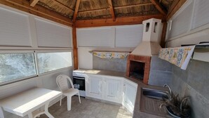 Una cucina compatta con forno integrato, un piccolo angolo ristoro con tavolo e sedia, e una finestra con vista sul verde.