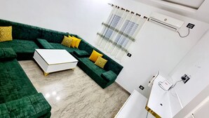 Un soggiorno moderno con un divano a divano verde, un tavolino da caffè bianco e cuscini gialli.