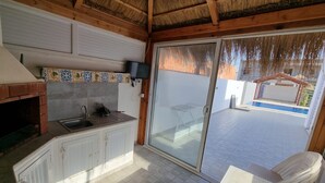 Una cucina con forno a mattoni, mobili bianchi, un lavello e un televisore montato a parete.