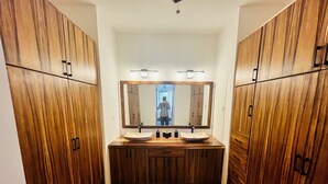 A bathroom with wooden cabinets, a large mirror, and two sinks.