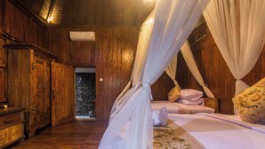 A wooden room with a bed, a wardrobe, and a door leading to a stone wall. - Green Zone Villas Ubud (Ubud)