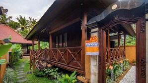 A wooden building with a porch, stone steps, and a garden with various plants. - Green Zone Villas Ubud (Ubud)