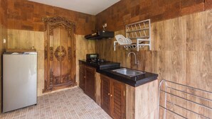 A compact kitchen with a refrigerator, wooden cabinets, a sink, and a dish rack. - Green Zone Villas Ubud (Ubud)