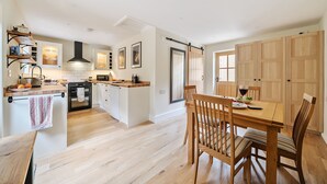 A modern kitchen with a central island, wooden cabinets, and a dining area with a table and chairs.