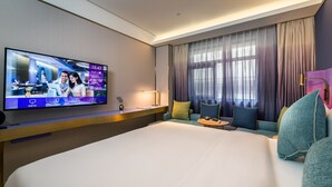 A hotel room with a large bed, a television mounted on the wall, a sofa, and a window with curtains. - Xi'an The Muslim Quarter Manxin Hotel (Xi'an)