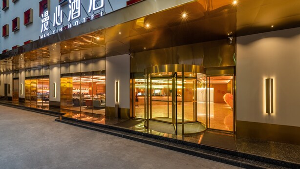 A hotel entrance with a glass facade, a revolving door, and a well-lit interior. - Xi'an The Muslim Quarter Manxin Hotel (Xi'an)