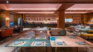 A modern dining area with tables set for four, a bar in the background, and a view of the lobby. - Xi'an The Muslim Quarter Manxin Hotel (Xi'an)