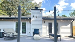 A covered patio with a white exterior, a chimney, string lights, and outdoor seating. - Charming 3-bedroom ranch home, back deck, close to ATL, in peaceful Norcross (Norcross)