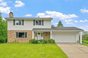 A two-story house with a stone facade, a garage, and a well-maintained lawn.