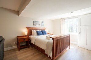 A bedroom with a wooden bed, bedside tables, a window with curtains, and a door.