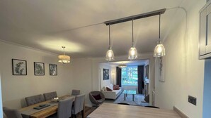 Eine moderne Küche mit einer zentralen Kochinsel, einem Essbereich mit Holztisch und -stühlen sowie einem Wohnbereich mit Sofa und Couchtisch.