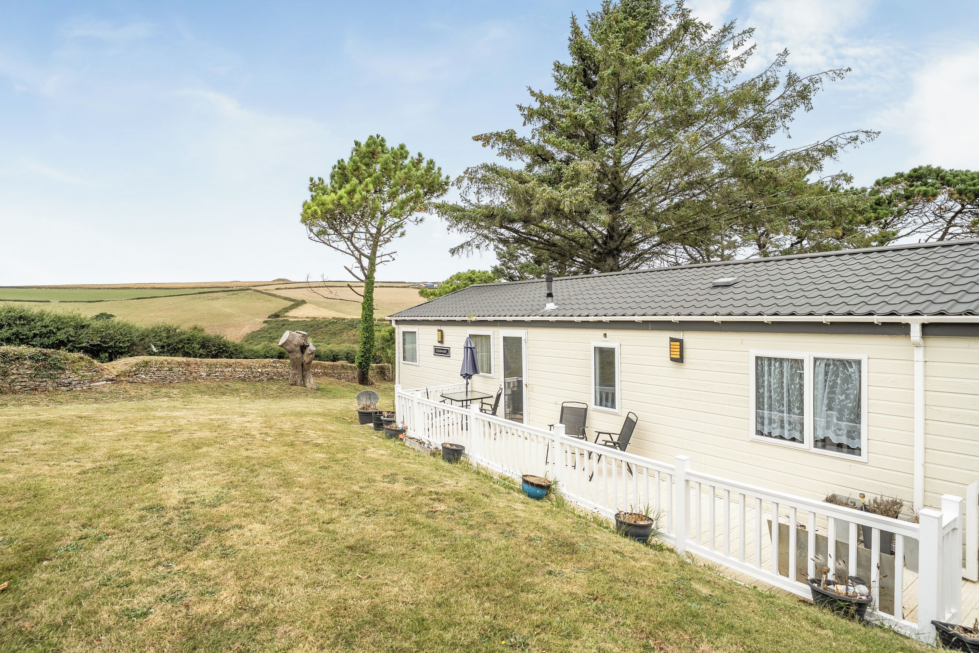 Einbungalow mit umzäunter Terrasse, einer kleinen Veranda und freiem Blick auf die umliegende Landschaft.