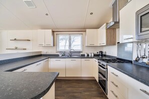 A modern kitchen with a central island, built-in oven, and stainless steel appliances.