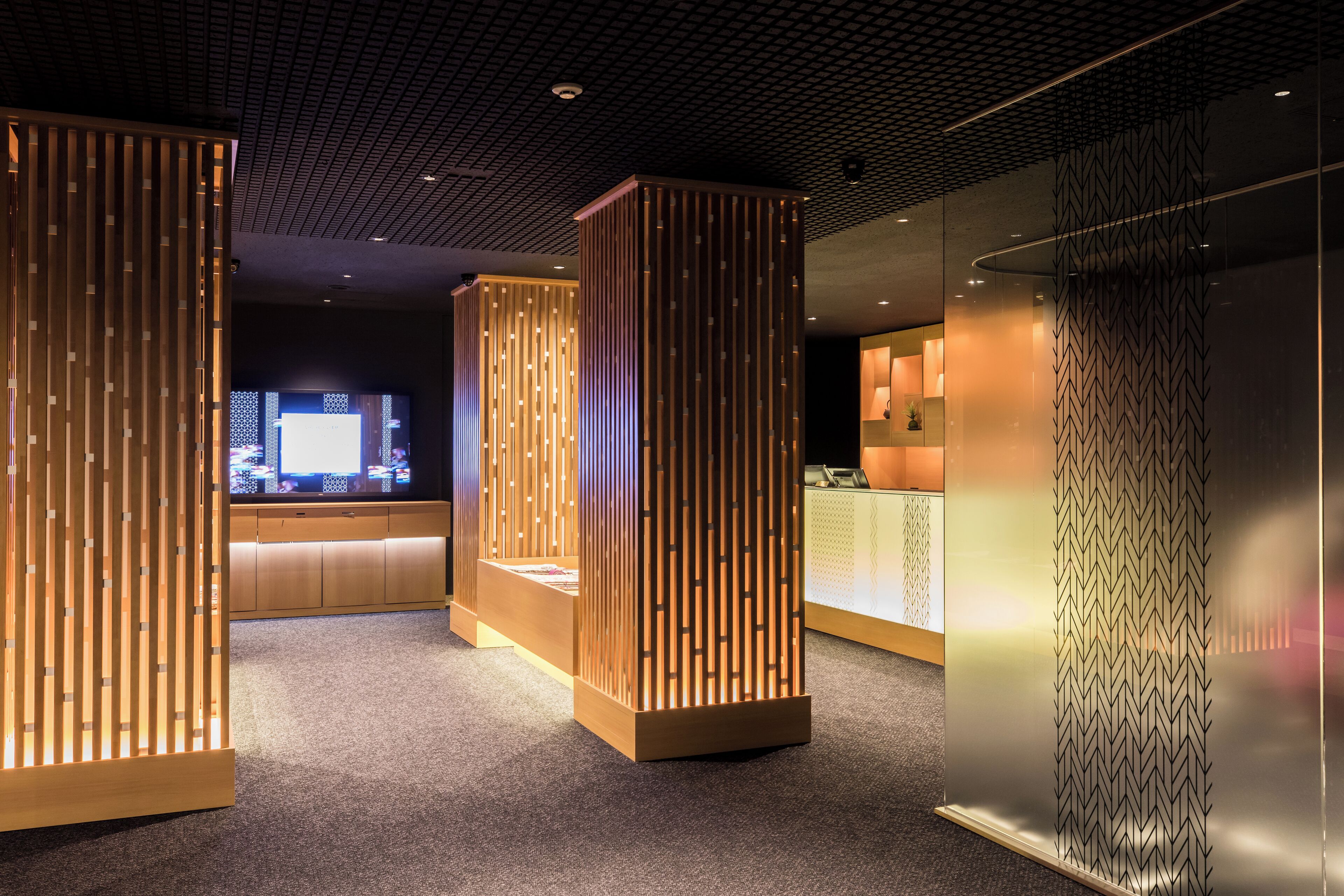 A modern interior with wooden partitions, a reception area, and a glass wall.