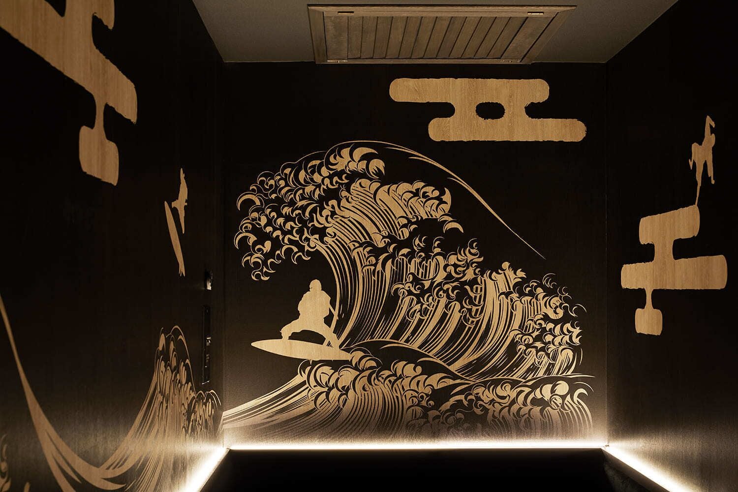 A room with a large wave painting on the wall, a ceiling vent, and a small table.