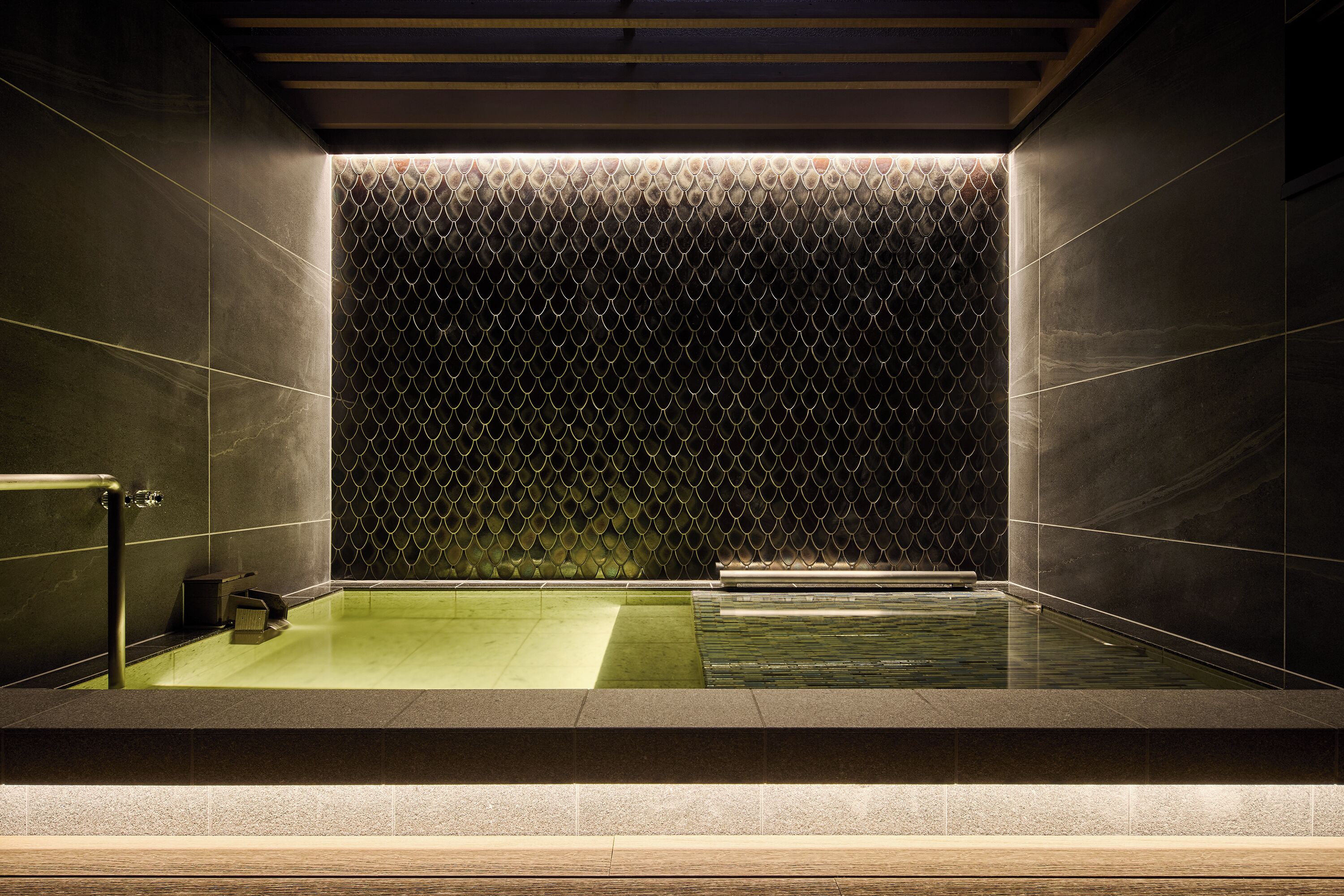 A modern bathroom with a geometric patterned wall, a rectangular bathtub, and a separate shower area.