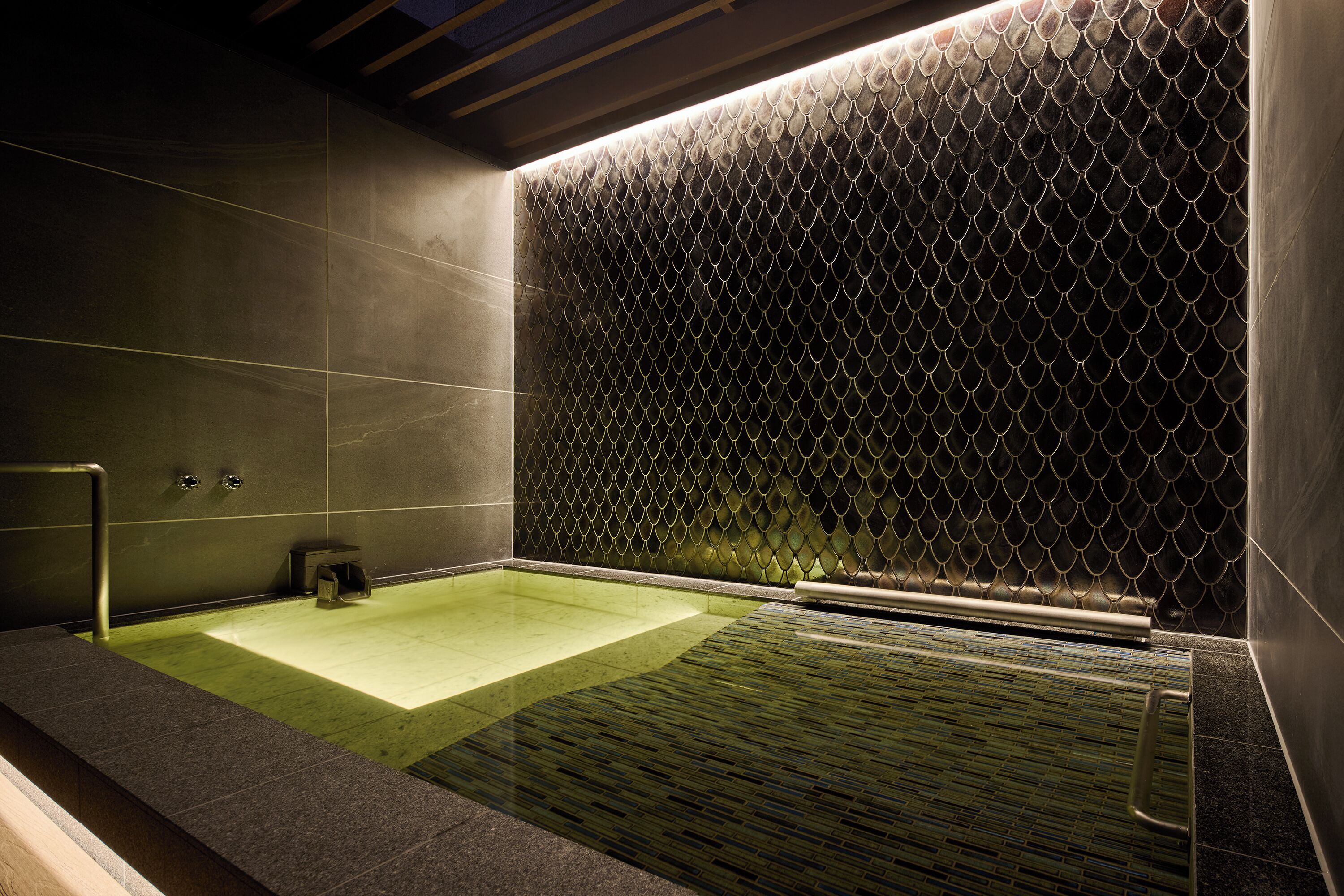 A modern bathroom with a large bathtub, a textured wall, and a minimalist design.
