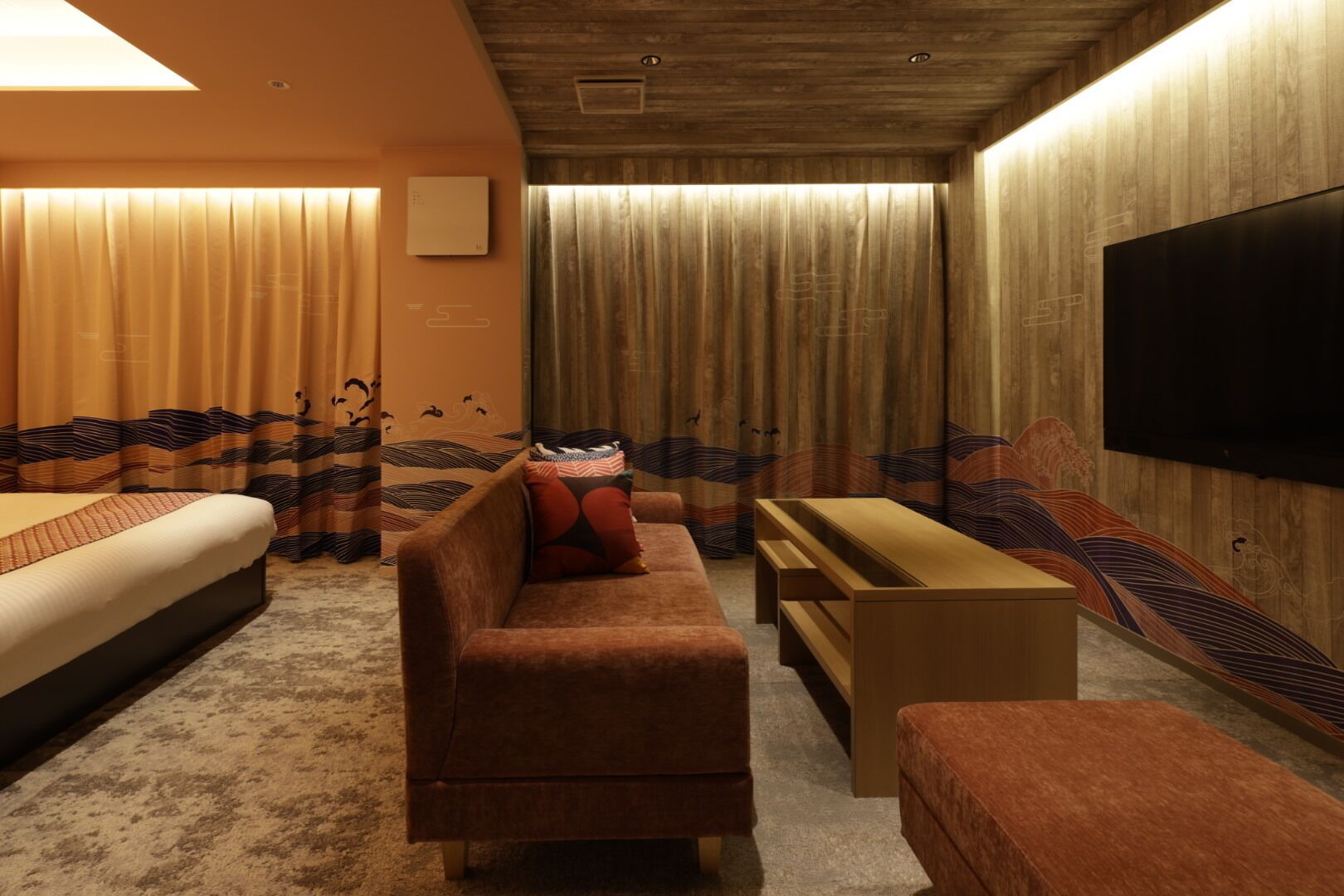 A modern hotel room with a sofa, a bed, a TV, and curtains.