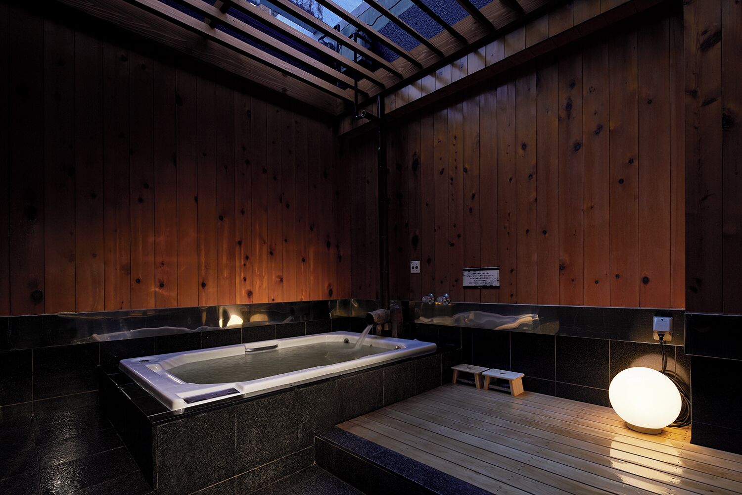 Une salle de spa avec un jacuzzi, des murs en bois et une terrasse en bois.