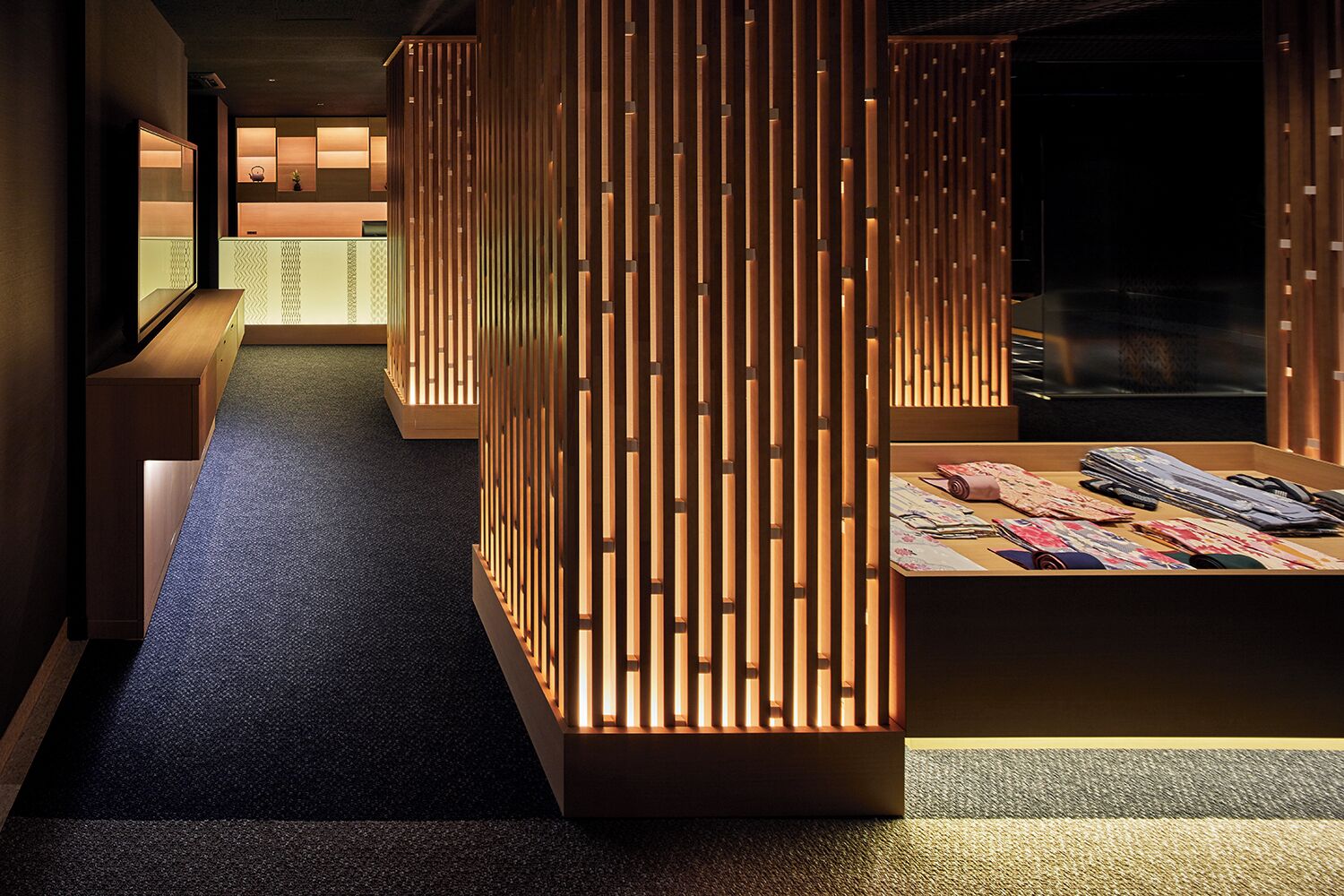 Un pasillo con un separador de madera, un mostrador de recepción y una exhibición de tejidos.