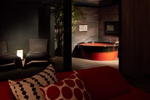 A spa room with a red bathtub, two wicker chairs, a red sofa with patterned pillows, and a wall-mounted sign. - Yatomi Hotel Nuqu Natural Hot Spring (Yatomi)