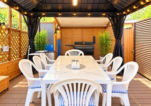An outdoor patio with a table and chairs, a grill, and a wooden fence. - Yamanakako Resort House I (Yamanakako)