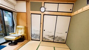 A tatami mat room with a tatami mat floor, a wooden ceiling, a wall clock, and a sliding door with a landscape painting. - Yamanakako Resort House I (Yamanakako)