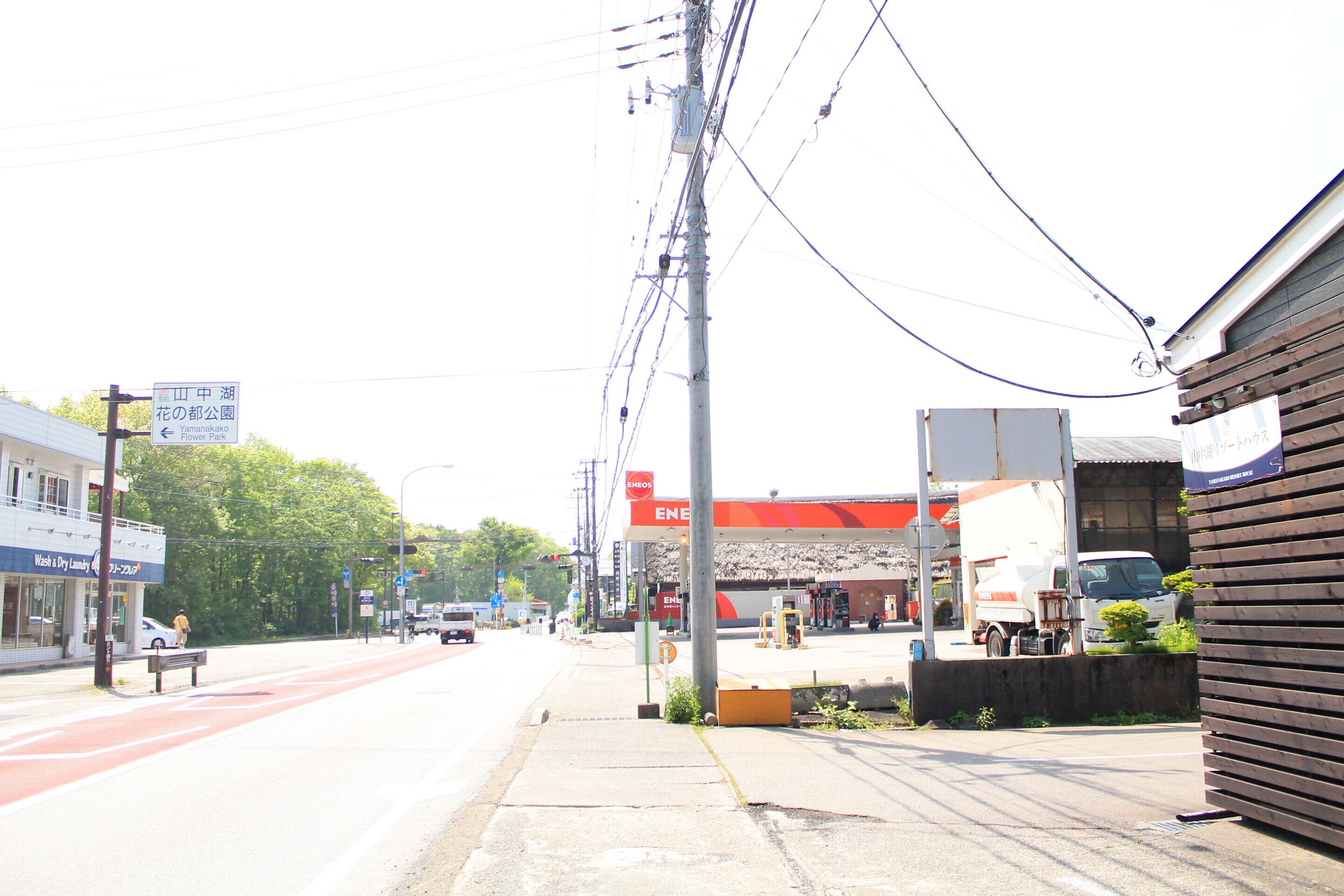 Une rue avec une station-service, un banc et un bâtiment portant une enseigne.
