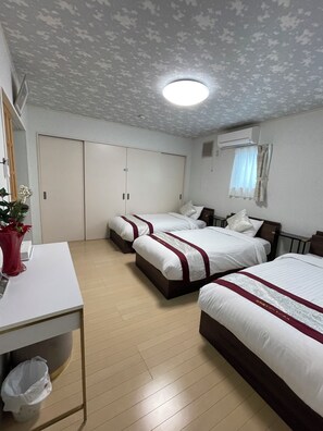 Een hotelkamer met twee bedden, een bureau, een prullenbak en een airconditioner.