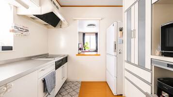 A compact kitchen with a stove, oven, microwave, refrigerator, and a window with a view.