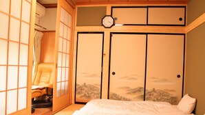 A traditional Japanese-style bedroom with tatami flooring, a futon bed, a shoji screen, and a sliding door with a landscape mural. - Yamanakako Resort House I (Yamanakako)