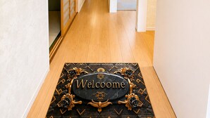 A hallway with a welcome mat, a wooden floor, and a door leading to a room. - Yamanakako Resort House I (Yamanakako)