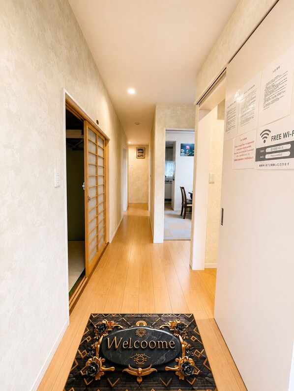 A hallway with a welcome mat, a wooden floor, and a door leading to a room. - Yamanakako Resort House I (Yamanakako)