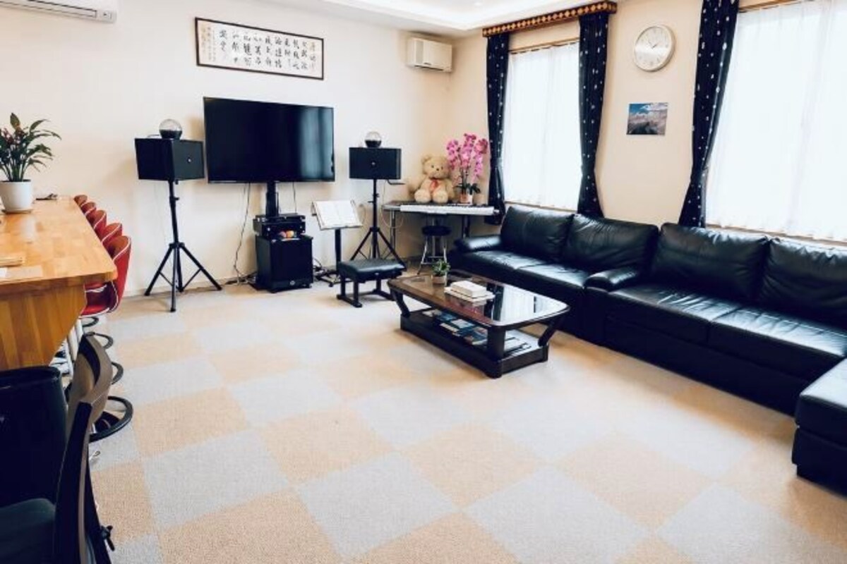 A living room with a sofa, coffee table, TV, speakers, and a plant.