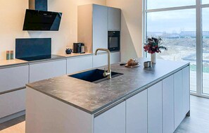 Een moderne keuken met een inbouwspoelbak, een flatscreen televisie en uitzicht op de stad.