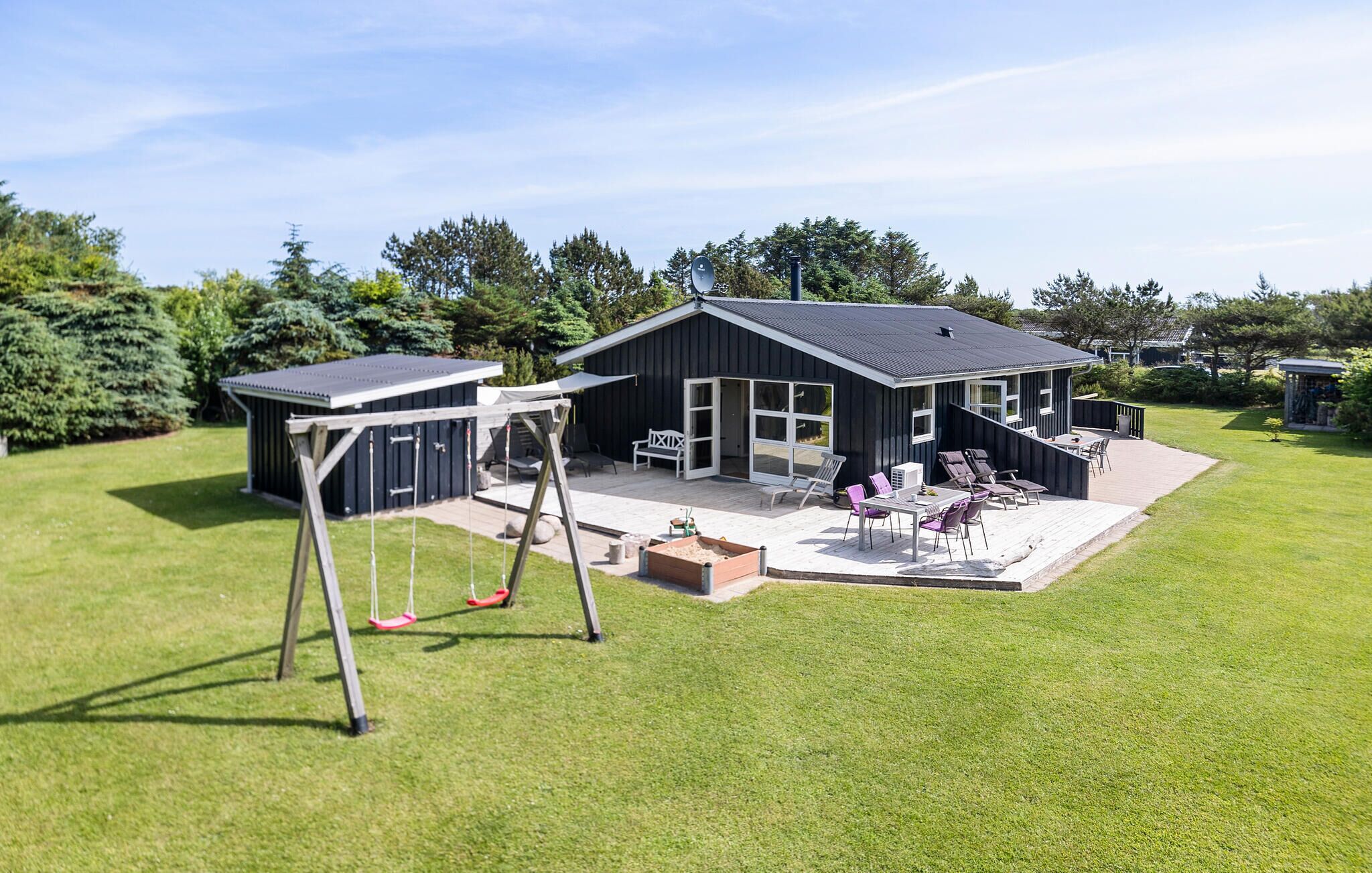 Ett modernt hus med en uteplats, en gunga och ett litet förråd.