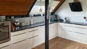 A modern kitchen with white cabinets, a wooden floor, and a black countertop. - Awesome home in Samsø with WiFi (Samsø)