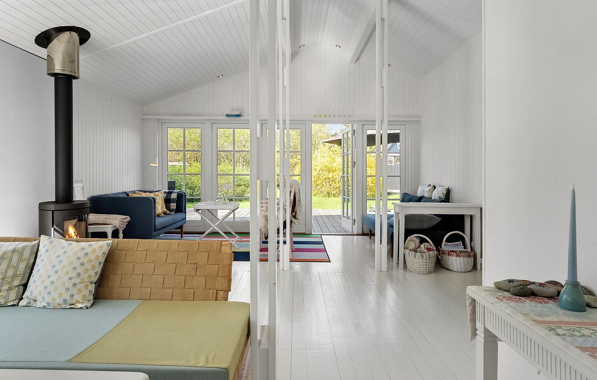 A spacious living room with a large window, a fireplace, a sofa, and a dining area.