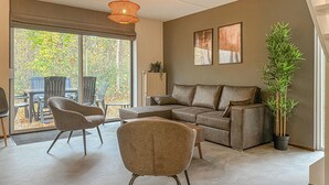 A living room with a sectional sofa, two armchairs, a large potted plant, and a dining area with chairs and a table. - 3 bedroom nice home in Hoeven (Hoeven)