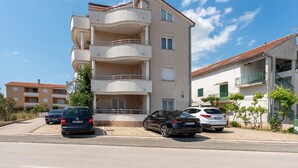 A multi-story residential building with balconies, parked cars, and a clear sky. - Nice apartment in Biograd na Moru with WiFi (Biograd na Moru)