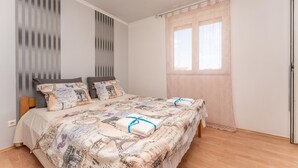 A bedroom with a bed, two pillows, a window with a curtain, and a door. - Nice apartment in Biograd na Moru with WiFi (Biograd na Moru)
