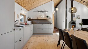 A modern kitchen with a wooden ceiling, white cabinets, and a built-in stove.