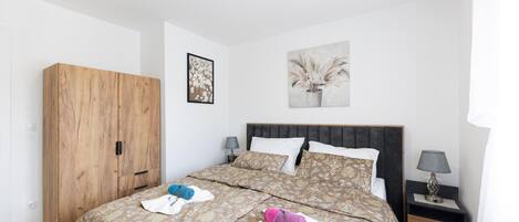 A bedroom with a bed, a wooden wardrobe, a nightstand, and two wall-mounted lamps.