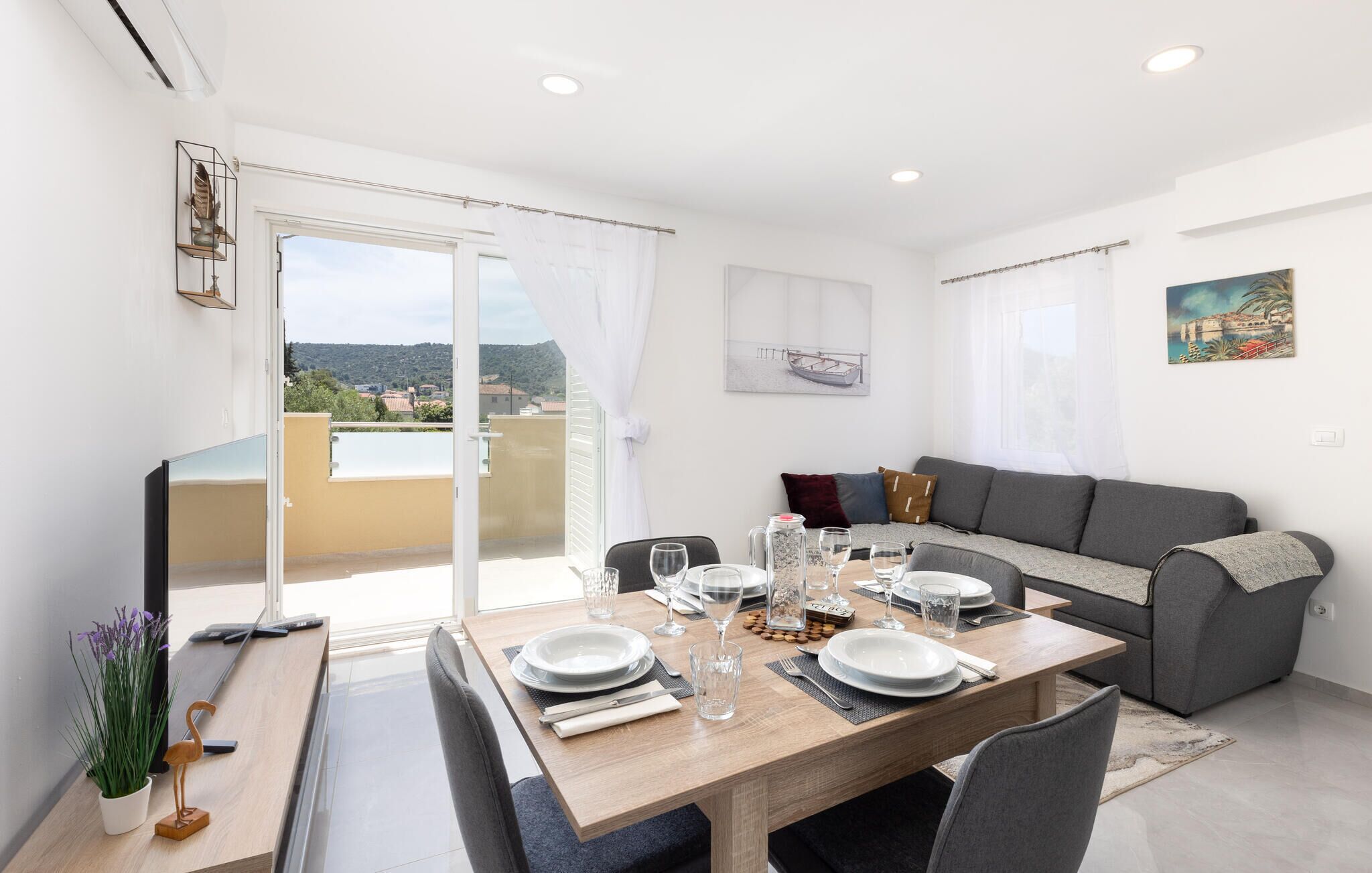 A modern living room with a dining area, a sofa, and a balcony with a view.