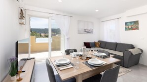 Een moderne woonkamer met een eethoek, een bank en een balkon met uitzicht.