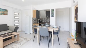 Een ruimtelijke leefruimte met een kitchenette, eethoek en een slaapbank.