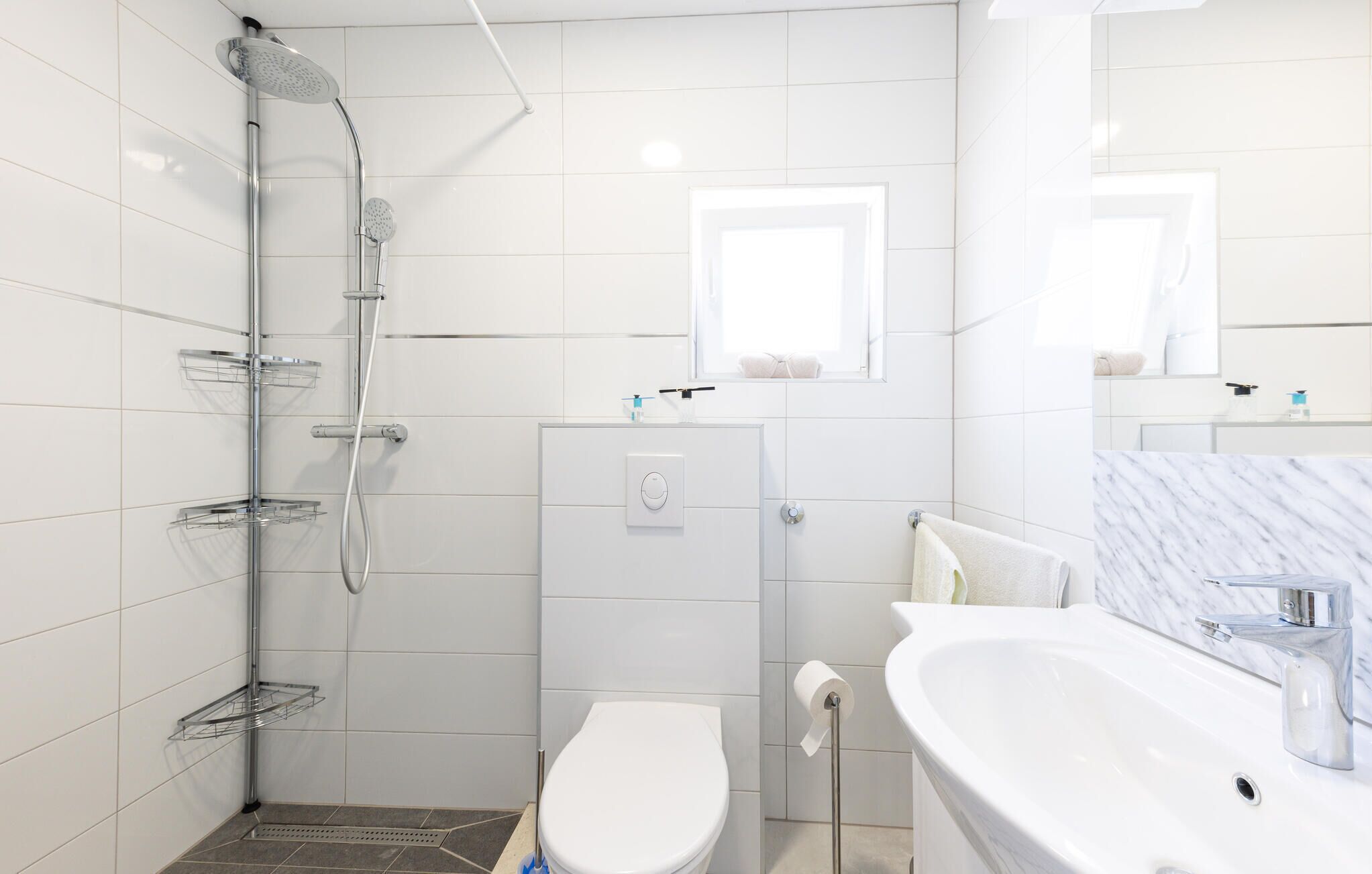 A modern bathroom with a shower, toilet, and sink.